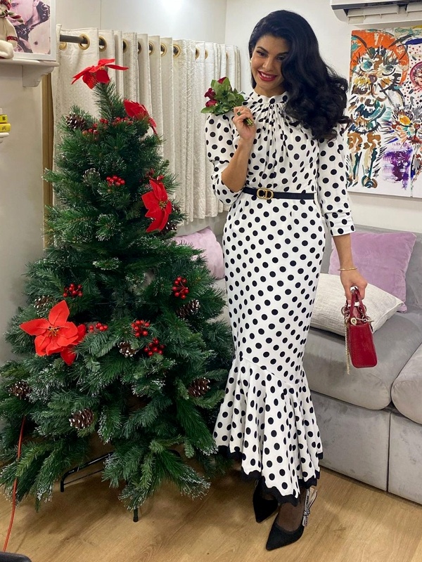 Jacqueline Fernandez wearing black and white polka dot maxi dress with asymmetrical ruffled hem and red purse