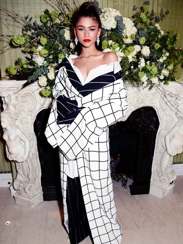 Zendaya in black and white grid pattern dress with asymmetric draped shoulders over pinstriped pants