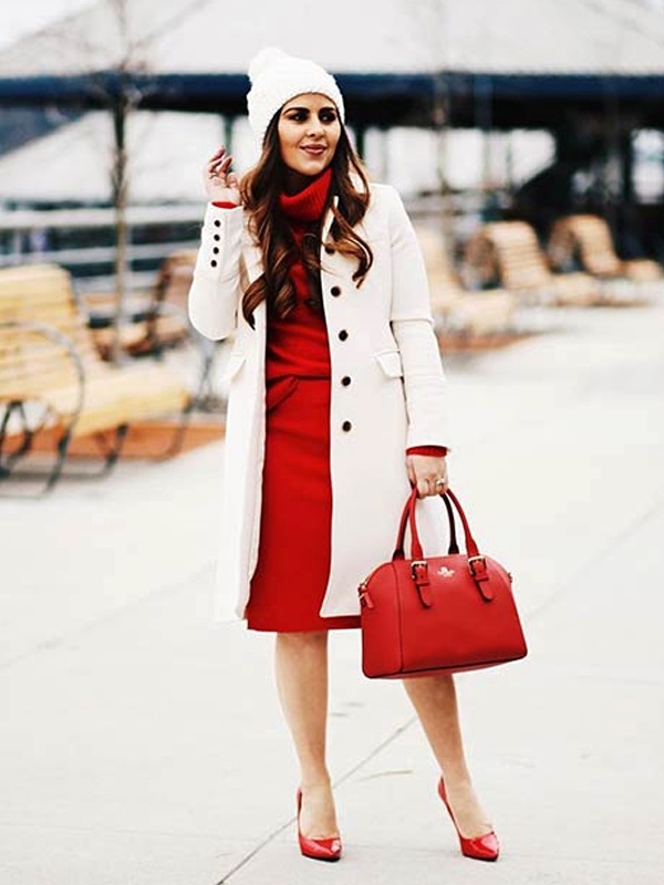 Woman wearing a red turtle neck dress with a white coat featuring buttons, red heels and carrying a red bag, perfect for a holiday celebration.