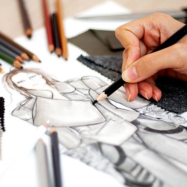 Fashion designer revisiting and transforming old dress sketches with new colors and details
