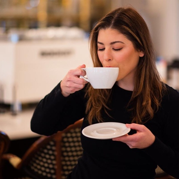 Designer creating calming workspace ritual with warm tea and soft lighting for creative focus
