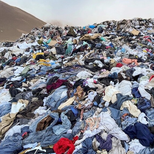 Massive landfill pile of textile waste, highlighting the 92 million tonnes of fashion waste dumped globally each year