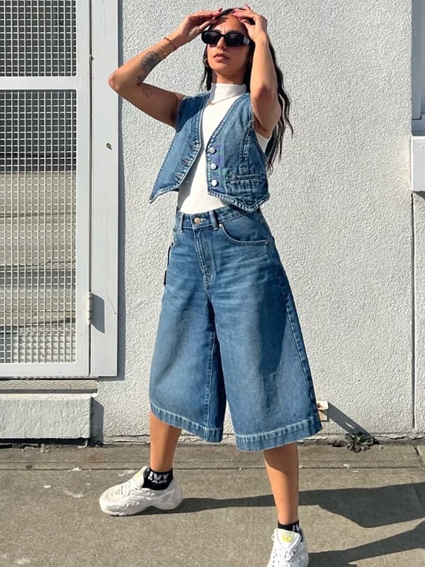 Woman in medium blue wide-leg denim culottes with vest - modern bohemian fashion trend