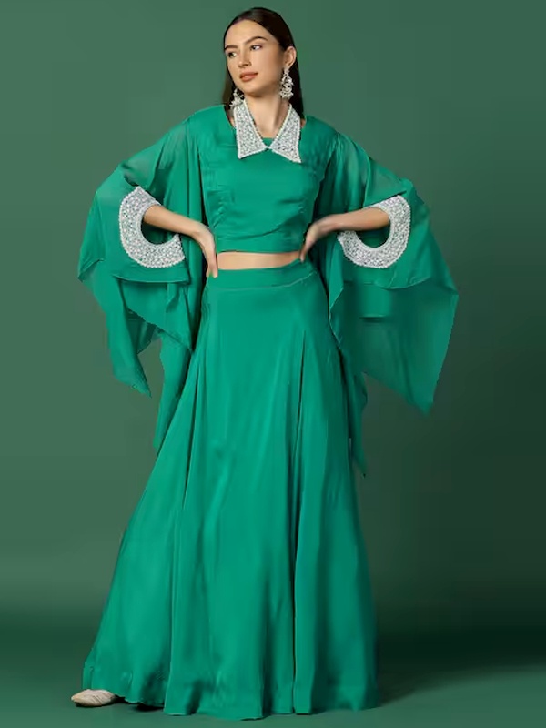 Green georgette crop top with pearl embroidered organza cape sleeves and detachable collar paired with a matching skirt. Green georgette crop top with pearl embroidered organza cape sleeves and detachable collar paired with a matching skirt.