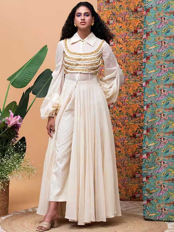 Ivory jute cape with balloon sleeves and gold details worn over a pearl embellished blouse and pants. Ivory jute cape with balloon sleeves and gold details worn over a pearl embellished blouse and pants.