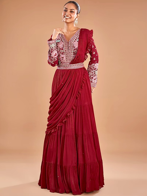 Deep red embroidered gown with attached ruffled drape and belt, featuring long sleeves and tiered skirt. Deep red embroidered gown with attached ruffled drape and belt, featuring long sleeves and tiered skirt.