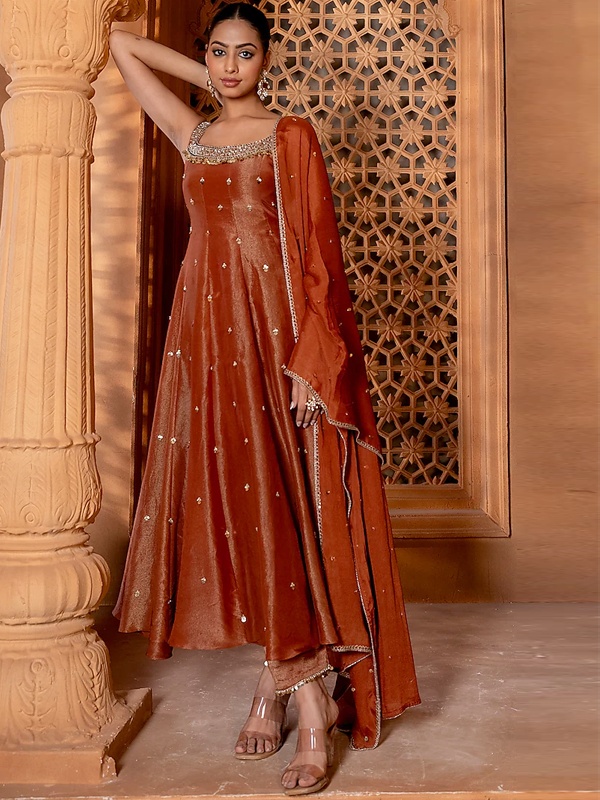 Rust brown silk anarkali with zari and sequin embroidery, featuring a square neckline and matching dupatta. Rust brown silk anarkali with zari and sequin embroidery, featuring a square neckline and matching dupatta.