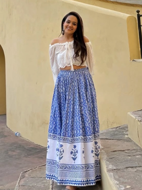 White off-shoulder crop top with sheer sleeves paired with a blue and white printed maxi skirt. White off-shoulder crop top with sheer sleeves paired with a blue and white printed maxi skirt.