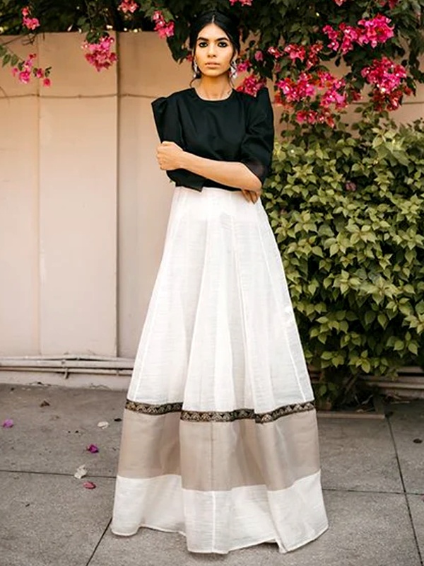 Woman wearing a black bodice with a white organza skirt, adorned with black lace detailing at the hem. Woman wearing a black bodice with a white organza skirt, adorned with black lace detailing at the hem.