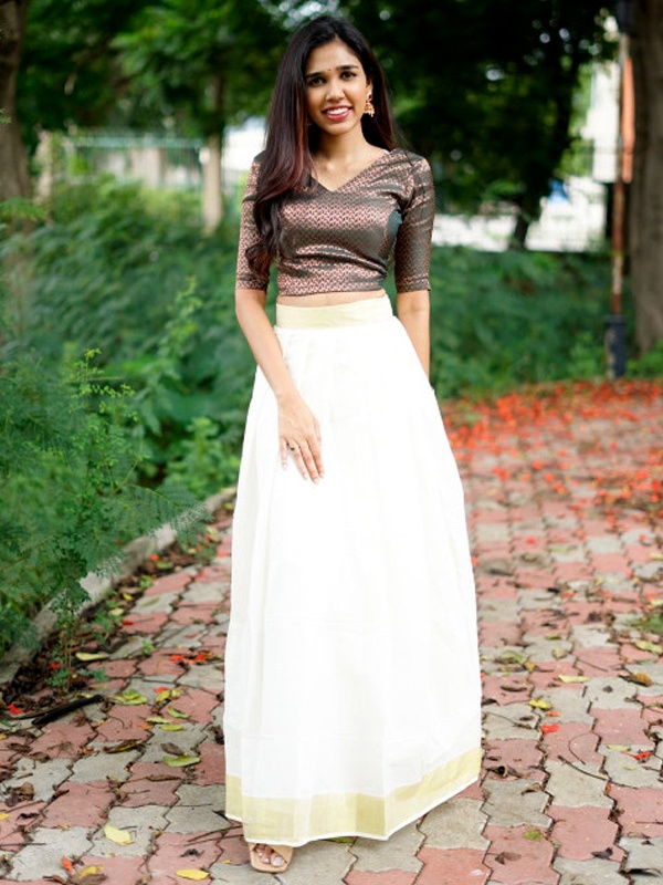 Woman in a brown and white lehenga with a gold waistband, standing on a brick pathway. Woman in a brown and white lehenga with a gold waistband, standing on a brick pathway.