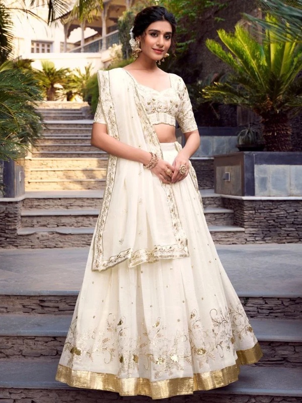 Cream lehenga with gold embroidery, showcasing intricate floral designs and sequins. Cream lehenga with gold embroidery, showcasing intricate floral designs and sequins.