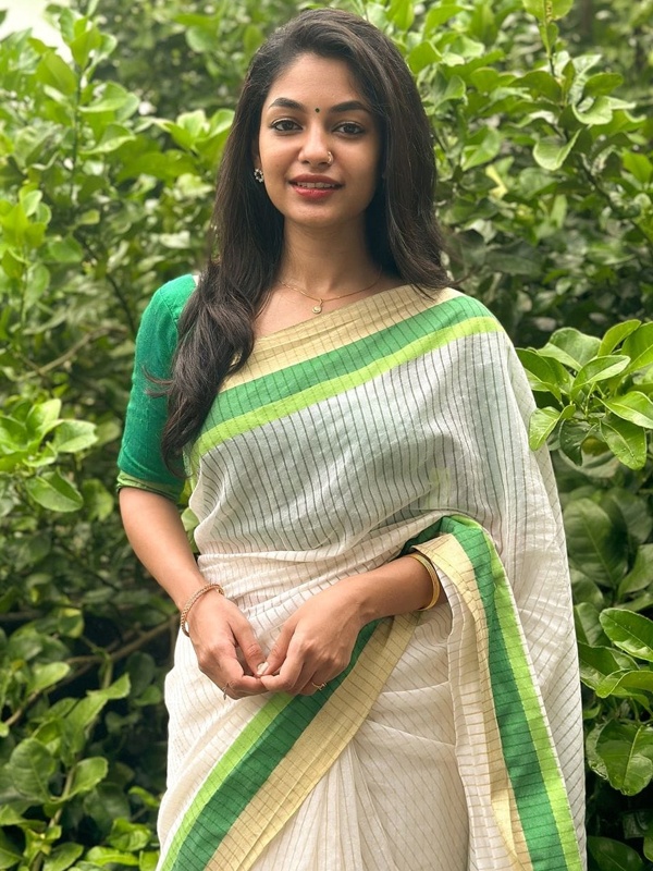 Woman in white striped saree with green and yellow accents and green blouse. Woman in white striped saree with green and yellow accents and green blouse.