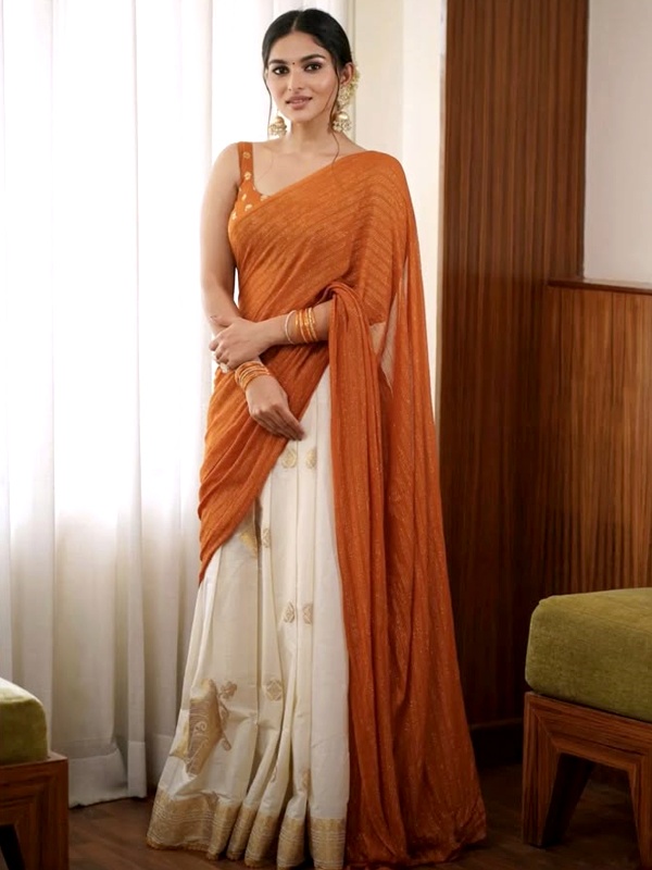 Actress Kayadu Lohar in an orange and cream saree with gold detailing, complemented by gold jewellery. Actress Kayadu Lohar in an orange and cream saree with gold detailing, complemented by gold jewellery.