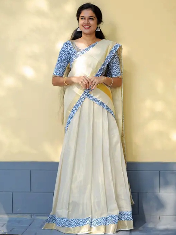 Woman in a white Kerala half saree with blue and white Ajrakh prints and gold Kasavu borders, representing regional craftsmanship. Woman in a white Kerala half saree with blue and white Ajrakh prints and gold Kasavu borders, representing regional craftsmanship.