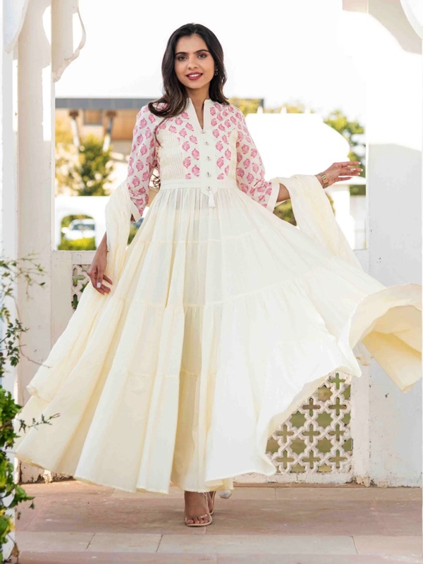 Woman in a tiered suit with a pink abstract design on the top and a white skirt, paired with beige sandals. Woman in a tiered suit with a pink abstract design on the top and a white skirt, paired with beige sandals.