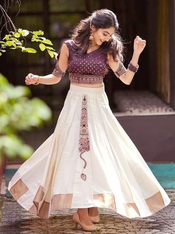 Woman in purple embellished top and white skirt for Onam festival. Woman in purple embellished top and white skirt for Onam festival.