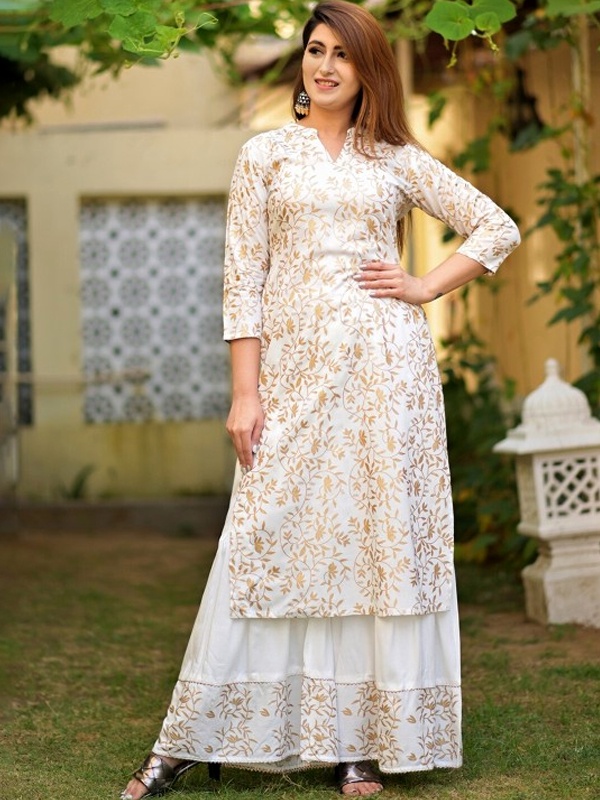 Woman in a white and gold floral kurta with sharara, showcasing detailed golden embroidery. Woman in a white and gold floral kurta with sharara, showcasing detailed golden embroidery.