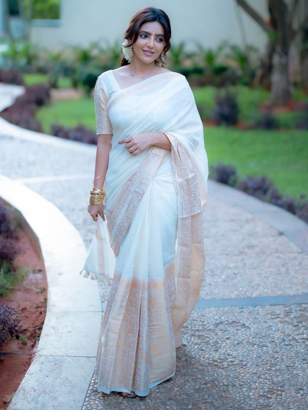 Woman wearing a white Vanasingari saree with a pastel border, exuding elegance. Woman wearing a white Vanasingari saree with a pastel border, exuding elegance.