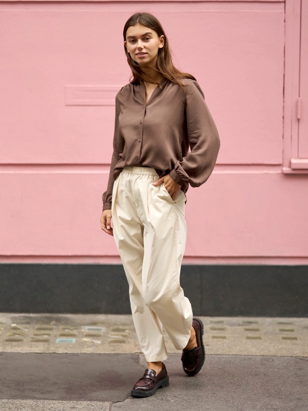 Women's business casual look featuring brown semi-formal shirt tucked into cream parachute trousers with dark loafers for smart college style