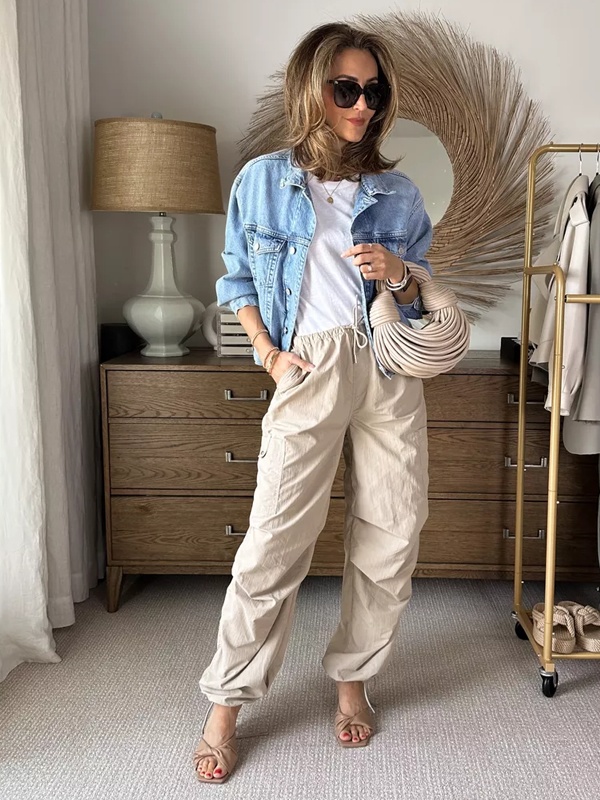 Mixed fabric styling with white cotton tee layered under blue denim jacket, beige parachute pants and tan sandals for textured college outfit