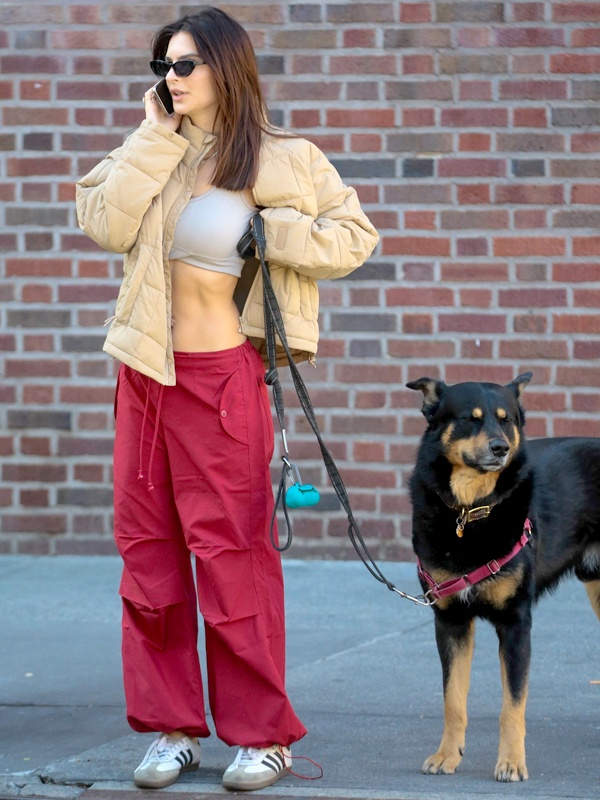 Winter layering outfit with grey ribbed crop top, bold red high-waisted parachute pants with cuffed ankles, beige puffer jacket and white sneakers