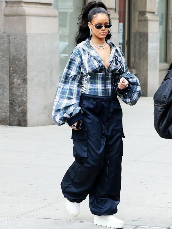 Pop icon Rihanna styling deep navy blue parachute trousers with plaid corseted button-down shirt featuring billowing sleeves and white platform boots