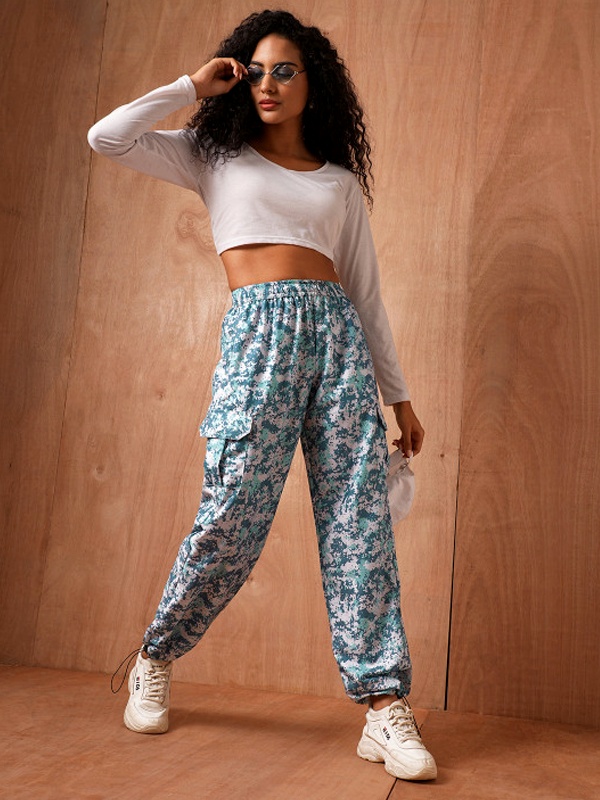 Eye-catching teal and white printed parachute pants paired with white long-sleeve crop top and sneakers for bold college statement look