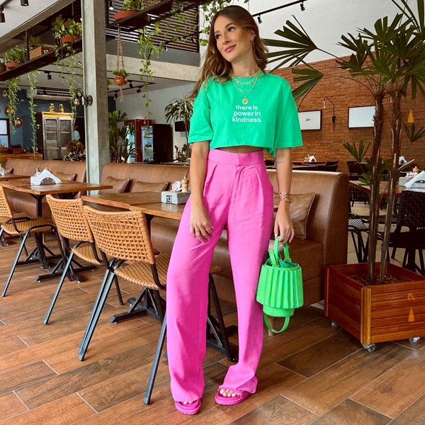 Pink trousers styled with olive green contrasting top and neutral footwear