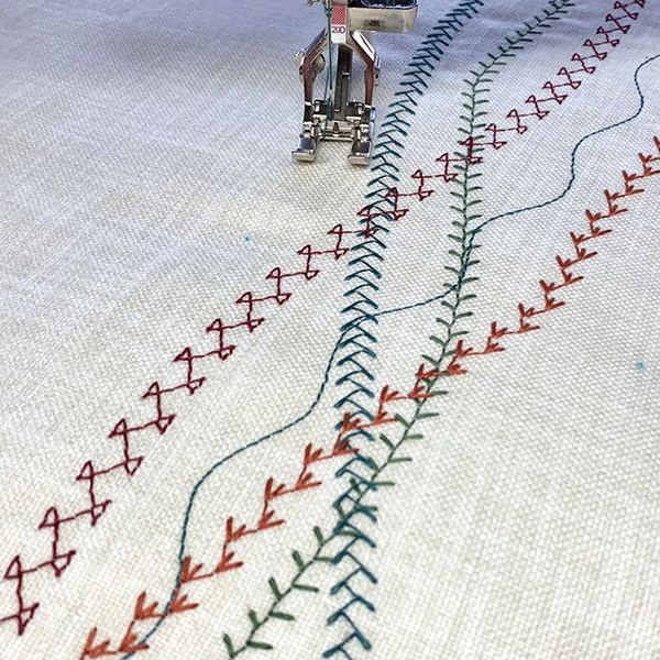 Programmable decorative stitch patterns on modern sewing machine showing complex geometric designs Programmable decorative stitch patterns on modern sewing machine showing complex geometric designs