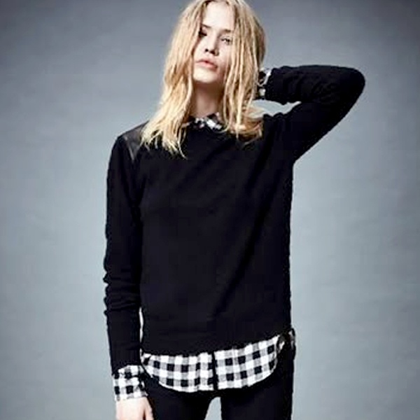 Bold pattern mixing black sleeveless sweater vest layered over blue and white checked flannel shirt for casual styling