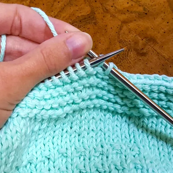 Close-up of various sweater vest knit construction techniques showing cable knit, ribbing and different yarn weights for fabric selection guide