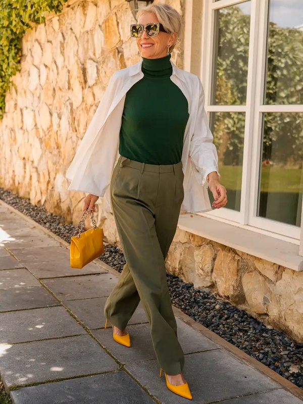 Bold color blocking forest green turtleneck under open white button-down shirt layered style with olive green pants bright yellow pointed toe heels and matching yellow leather handbag