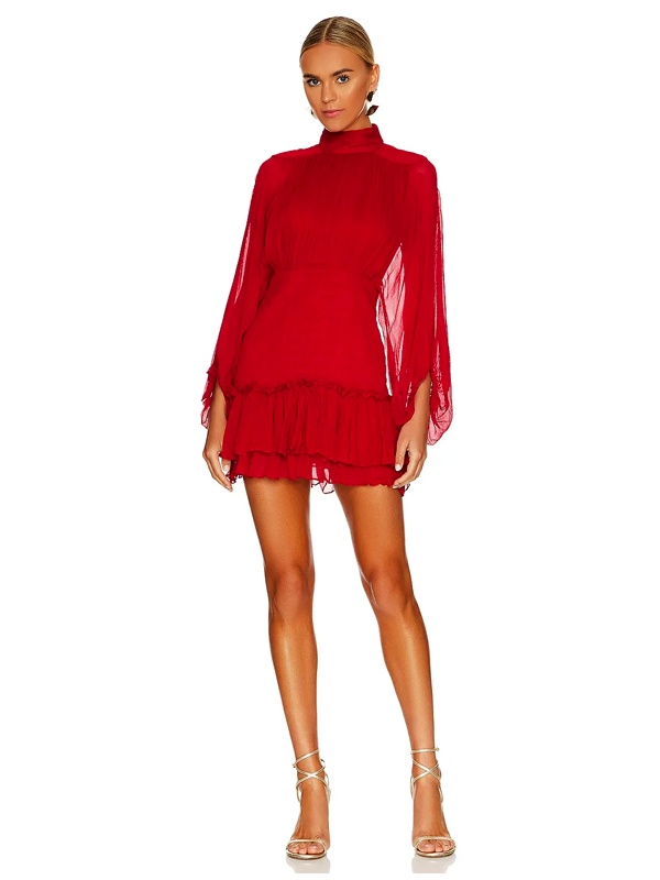 Woman wearing red long sleeve mini dress with high neckline, sheer billowing chiffon sleeves, tiered ruffle hem, paired with gold strappy heels
